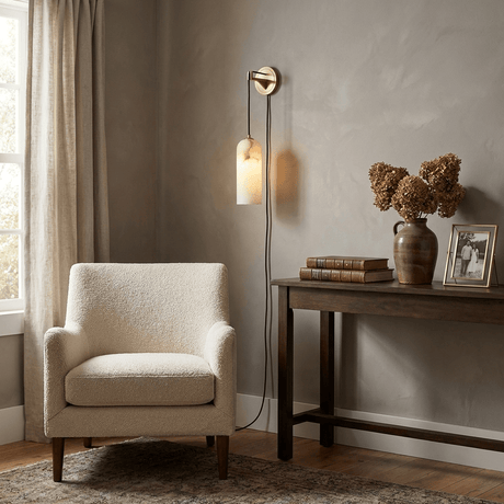 The lit lamp beside a curtain above a console with vases and books