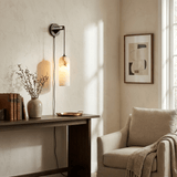 The lit lamp above a wood desk with a vase beside a cream armchair