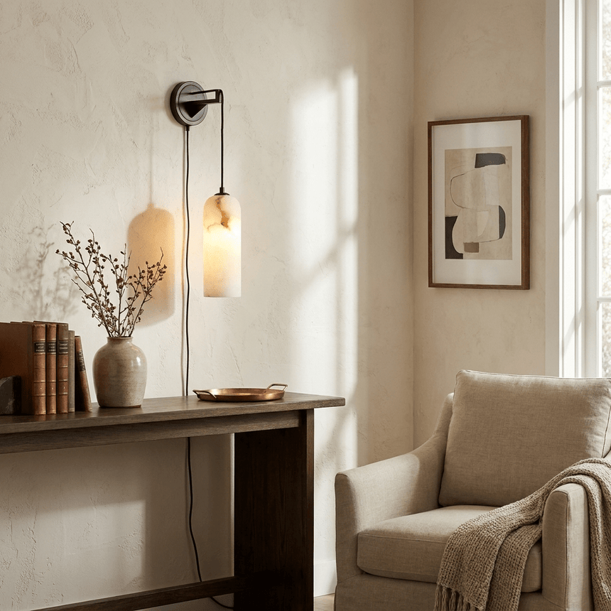 The lit lamp above a wood desk with a vase beside a cream armchair