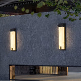 Two lit on a dark garden wall above a bench and a low stone plinth