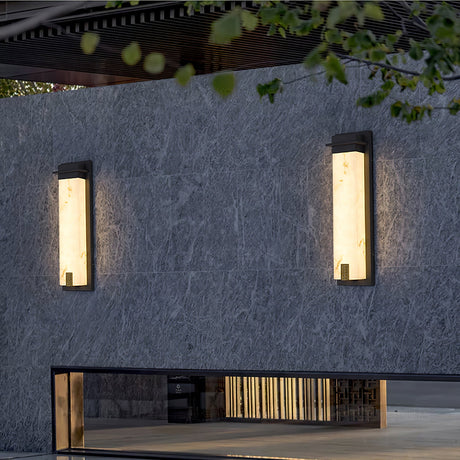 Two lit on a dark garden wall above a bench and a low stone plinth