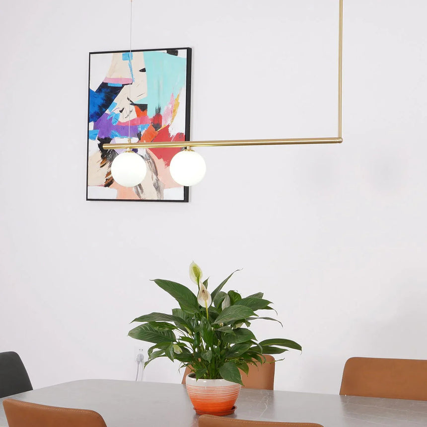 Brass frame hung in front of a bright artwork above a potted plant