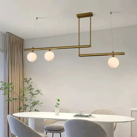 Brass frame with globes above a pale table beside a curved banquette