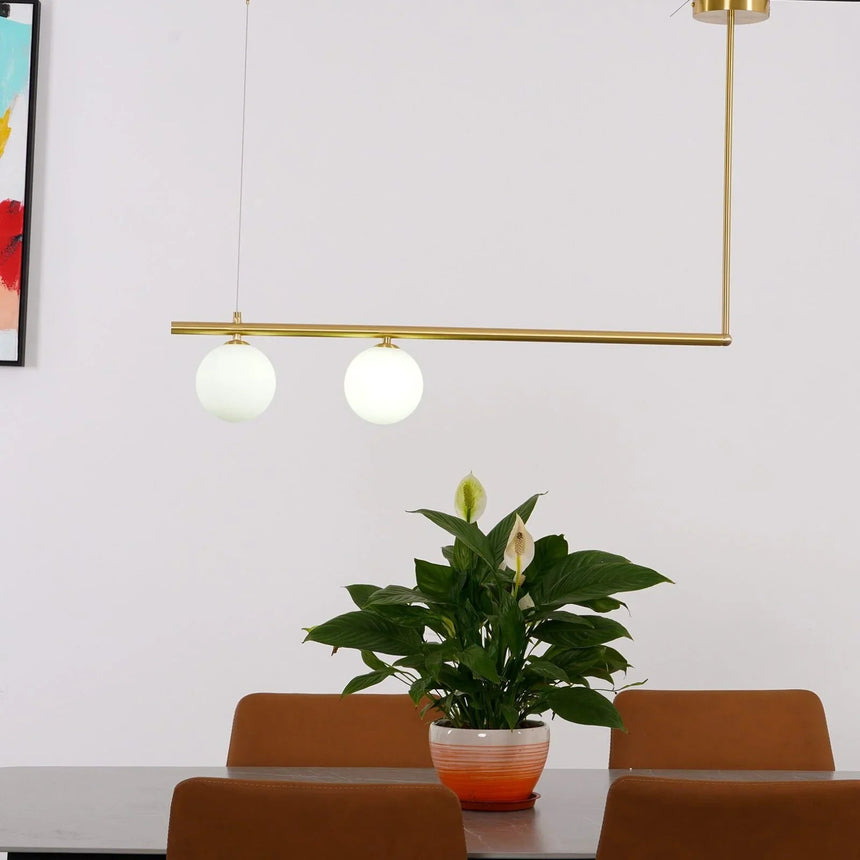 Two globes on a brass frame above a dining table with a tall plant
