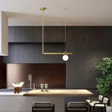 Brass arm with an opal globe reaching over a dark kitchen island