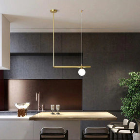 Brass arm with an opal globe reaching over a dark kitchen island