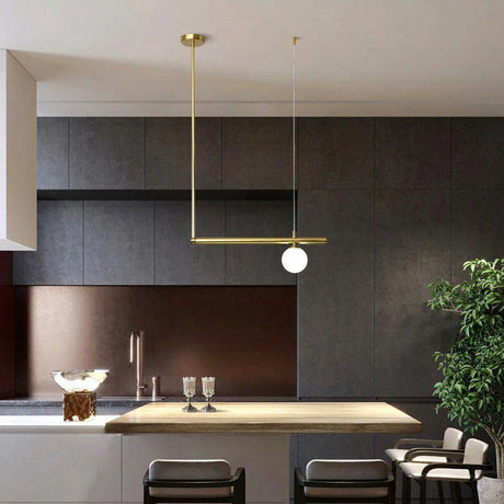 Brass arm with an opal globe reaching over a dark kitchen island