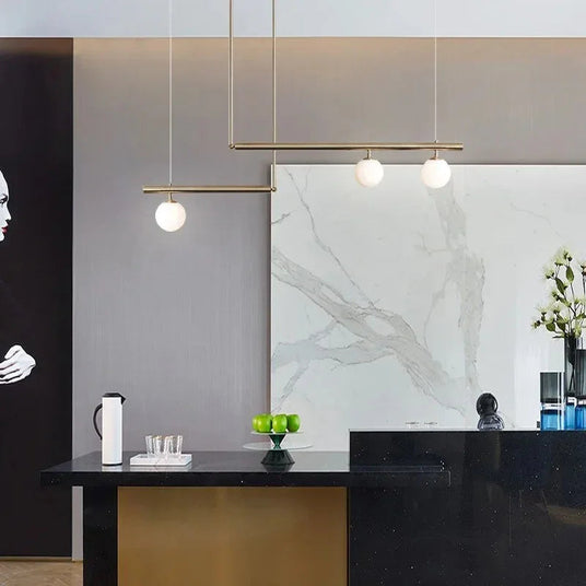 Arms with globes reaching across a marble counter in a bright kitchen