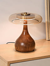 Table lamp with a glass shade lit beside a leaning mirror