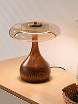 Table lamp with a glass shade lit on a sideboard with a basket