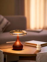 Table lamp with a glass shade lit on a coffee table beside a sofa