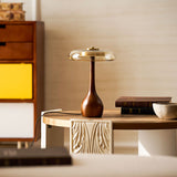 Table lamp with a glass shade lit on a round side table by a screen