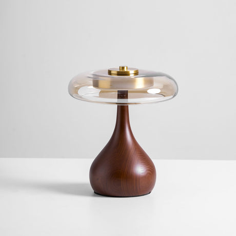 The short glass shade table lamp lit against a plain pale ground