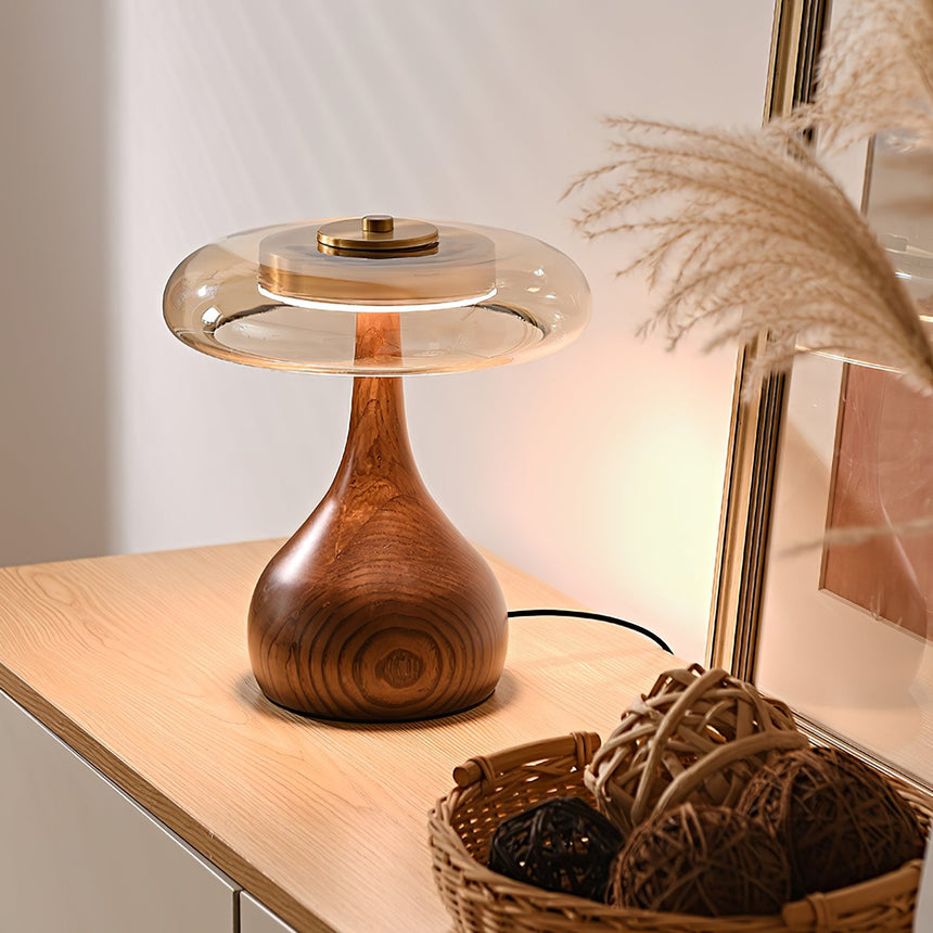 Table lamp with a glass shade lit beside dried pampas grass