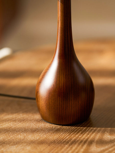 Close view of the curved walnut base of the glass shade table lamp