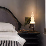 Table lamp with night light lit on a nightstand beside a made bed