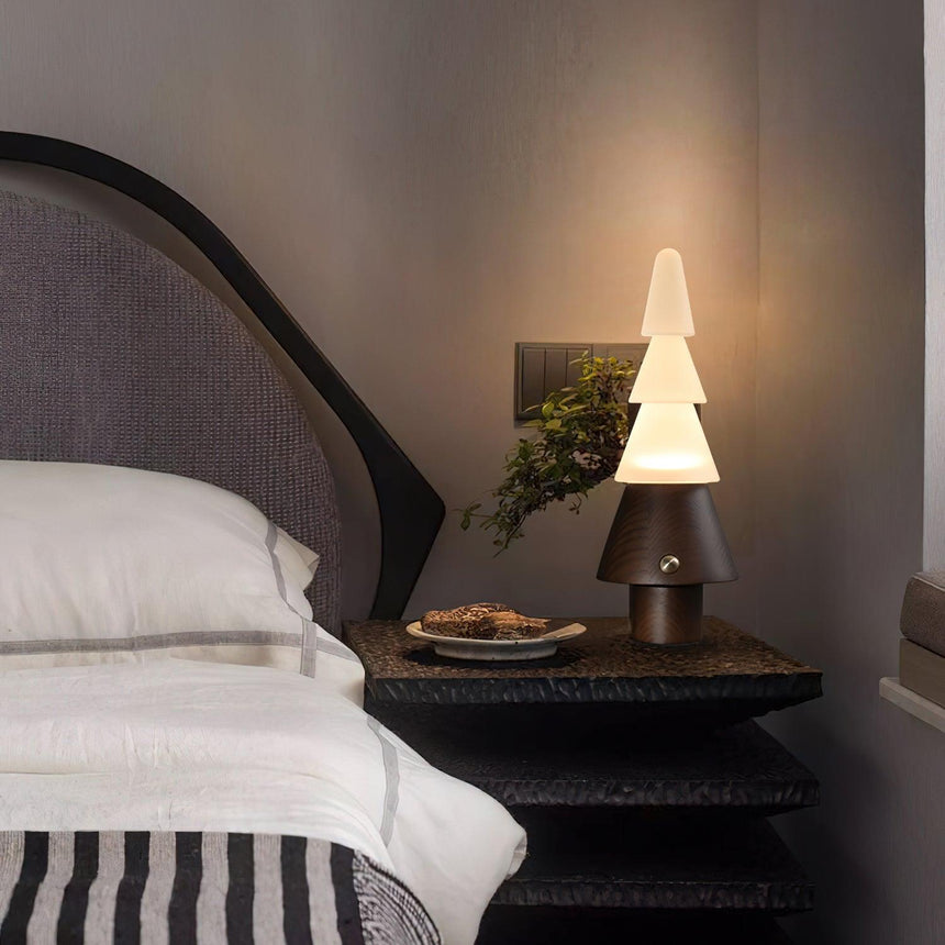 Table lamp with night light lit on a nightstand beside a made bed