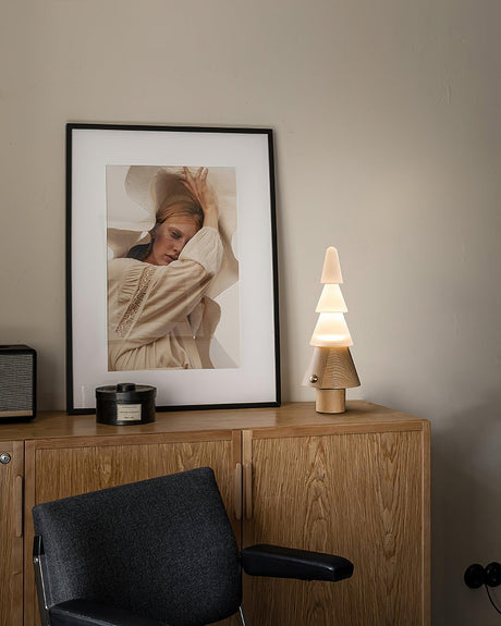 Table lamp with night light lit on a wooden cabinet beside a print