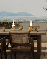 Two stacked tree lamps lit on a long table with a view behind