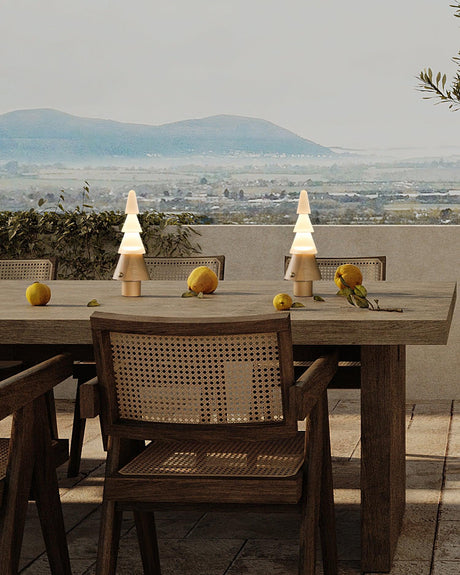 Two stacked tree lamps lit on a long table with a view behind