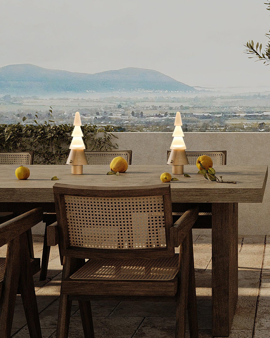 Two stacked tree lamps lit on a long table with a view behind