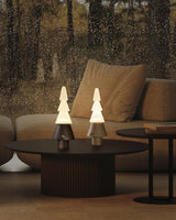 Two stacked tree lamps lit on a round coffee table by a sofa