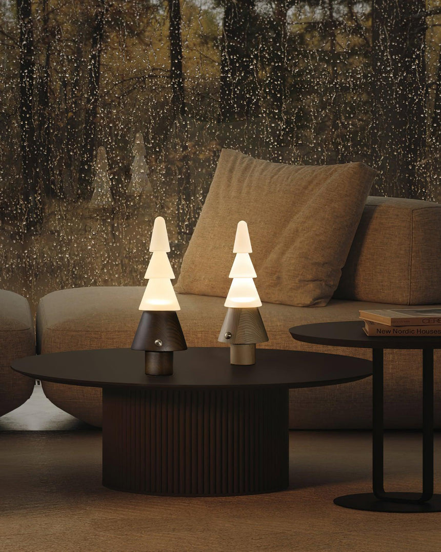 Two stacked tree lamps lit on a round coffee table by a sofa