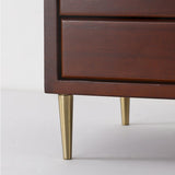 Close view of the tapered brass legs under the wooden drawer case