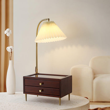 Table lamp with storage lit on a table beside a tall white vase
