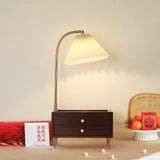 Table lamp with storage lit in a warm room beside a card and a tray