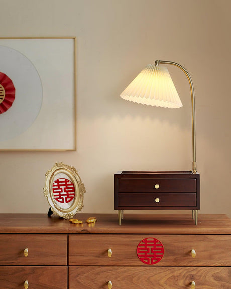 Table lamp with storage lit on a wooden sideboard beside a framed disc
