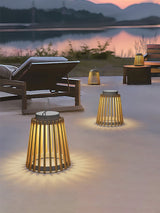 Two lanterns lit on a terrace at sunset beside a lounger and a lake