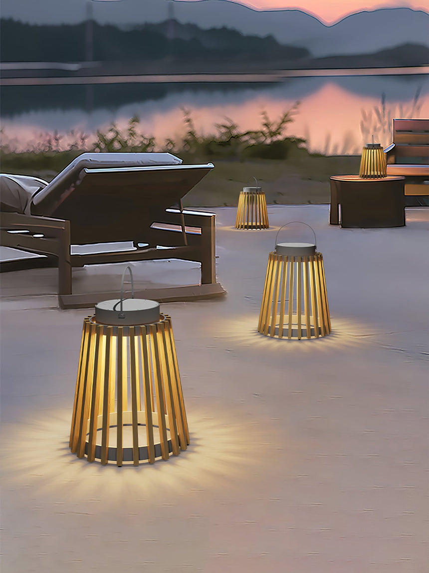 Two lanterns lit on a terrace at sunset beside a lounger and a lake