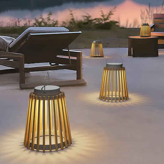 Two lanterns lit on a pool terrace beside loungers and a low table