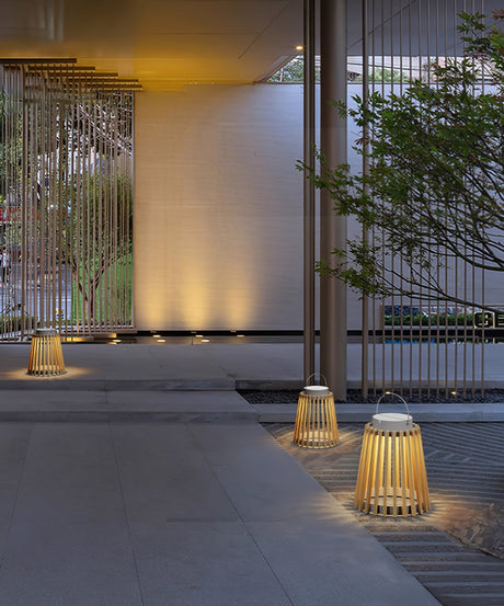 Lanterns lit on paving beside a slatted screen and a garden tree