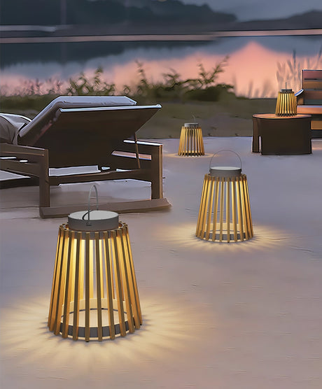 Two lanterns lit on a terrace beside a lounger with hills behind at dusk