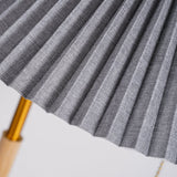 Close view of the gray pleated fabric against the brass pole