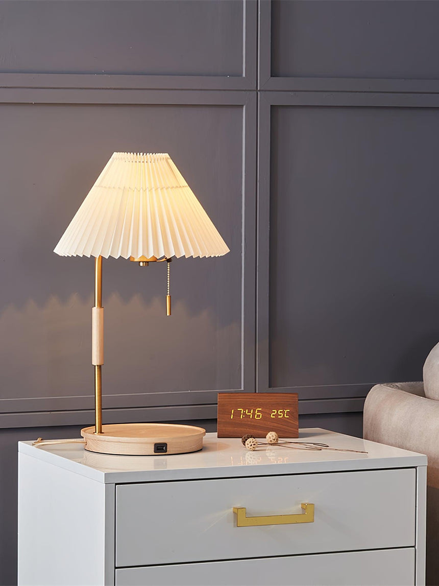 Pleated shade lamp lit on a nightstand beside a small clock