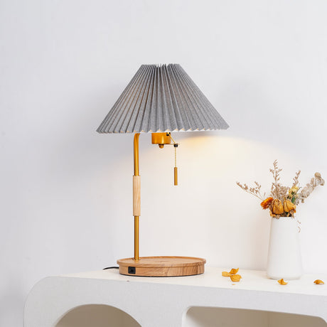 Pleated shade lamp lit on a plaster console beside dried flowers