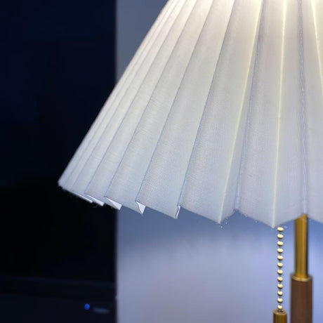 Close view of the lit pleated shade with the pull chain hanging