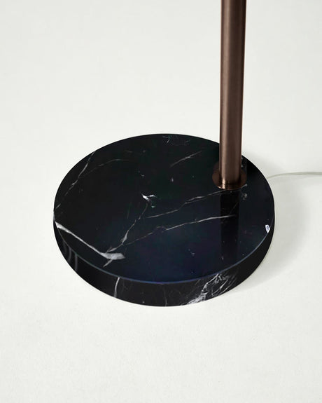 The round black marble base seen close with the bronze pole set into it