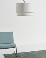 The shade hanging above a pale blue lounge chair on a green rug