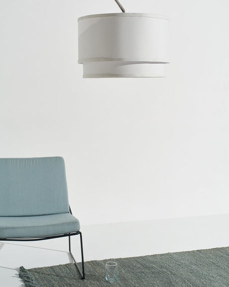 The shade hanging above a pale blue lounge chair on a green rug