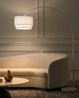 The arc lit over a cream curved sofa and a low table against a paneled wall