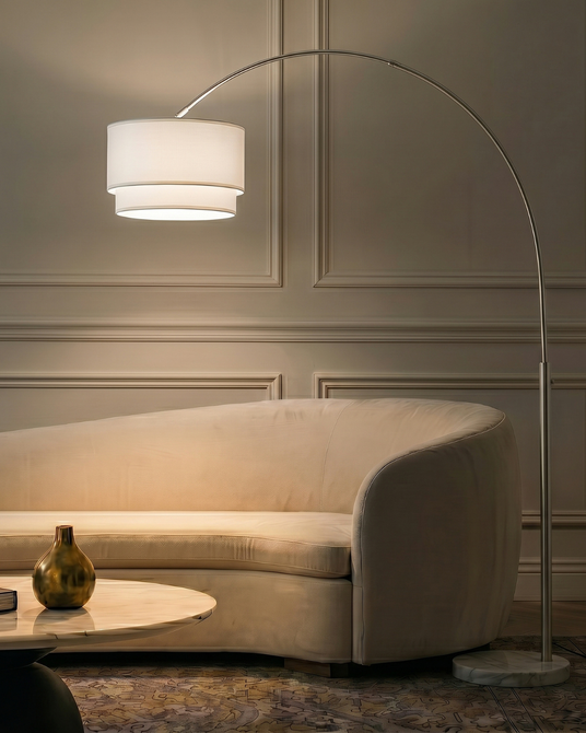 The arc lit over a cream curved sofa and a low table against a paneled wall