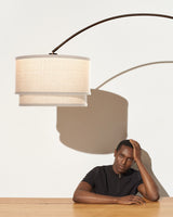 The oatmeal shade over the same wood table, a seated figure below it