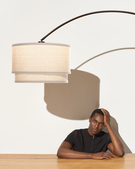The oatmeal shade over the same wood table, a seated figure below it