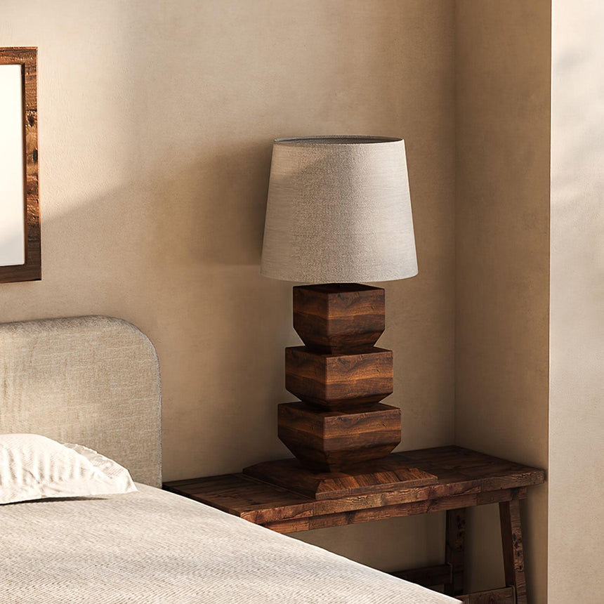 Tall table lamp on a bench beside a bed with a pale headboard