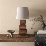 Tall table lamp on a wooden sideboard beside a bowl and a dark vase
