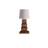 Tall table lamp seen in full, white drum shade over four stacked wood blocks